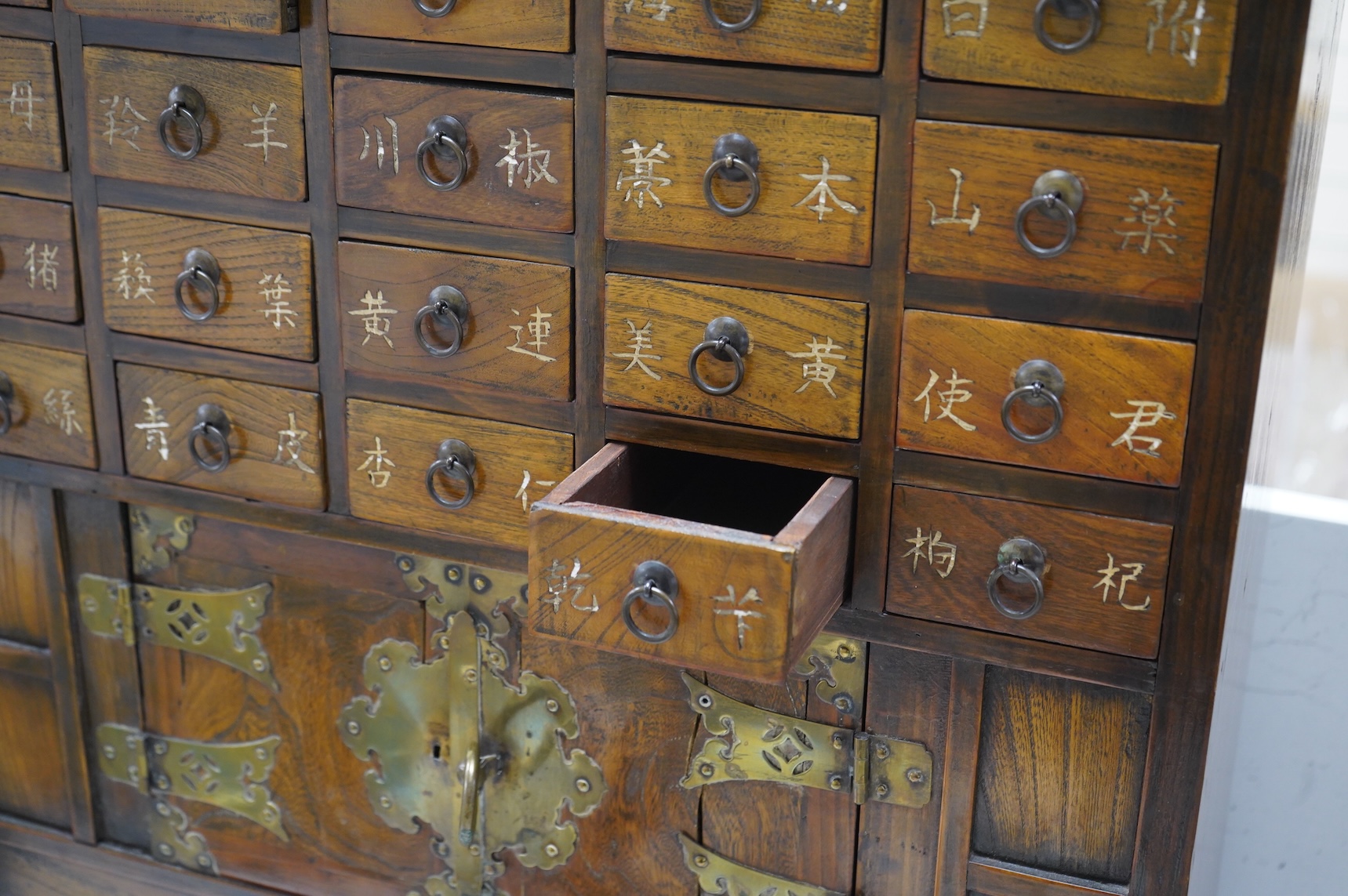 A Korean brass mounted chest with fitted drawers, decorated with calligraphy, 64cm high